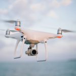 Drone - close up photography of drone flying over body of water at daytime