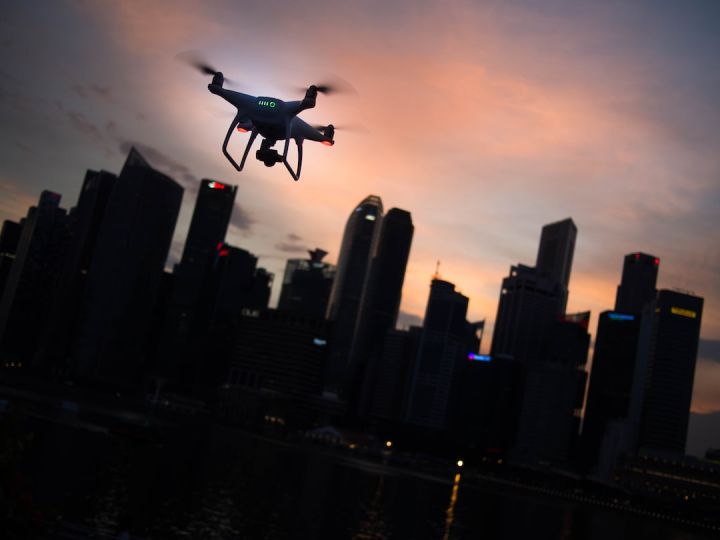 Drone - silhouette of quadcopter drone hovering near the city