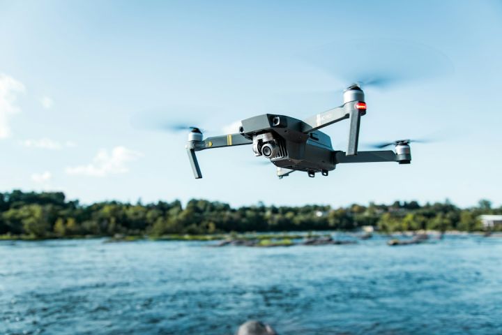 Drone - black DJI Mavi quadcopter near body of water