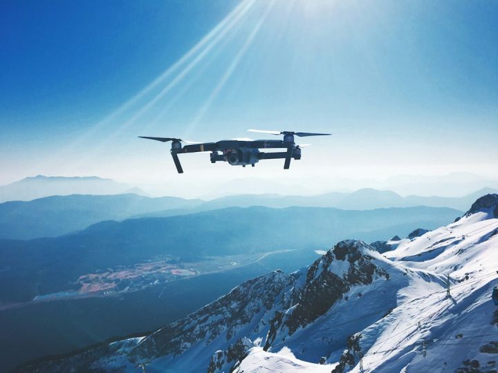 Drone - white quadcopter drone flying near snow mountain during daytime