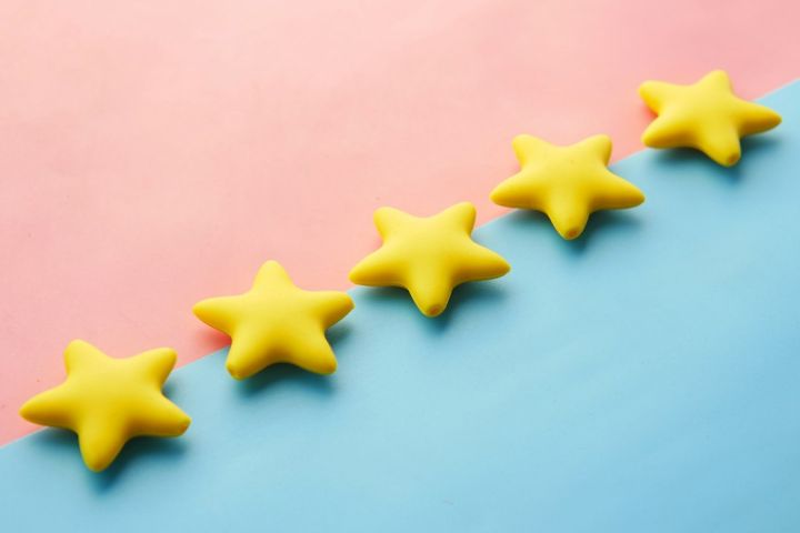 Review - a row of yellow stars sitting on top of a blue and pink surface