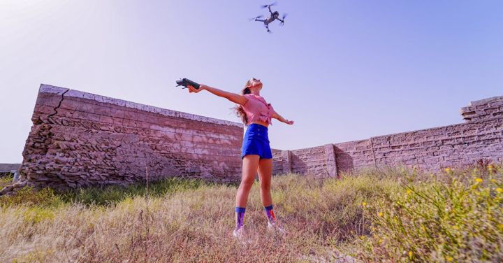 Remote Control Planes - Fit woman standing with arms outstretched under flying drone