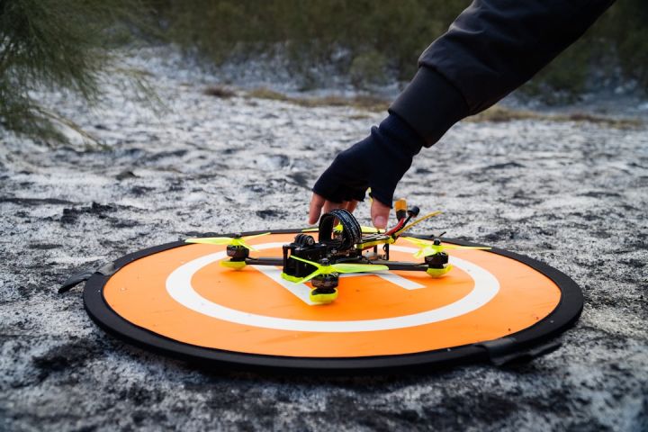 Fpv - a person holding a remote control helicopter on top of a field